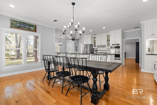 dining area featuring light wood-type flooring, crown molding, and an inviting chandelier