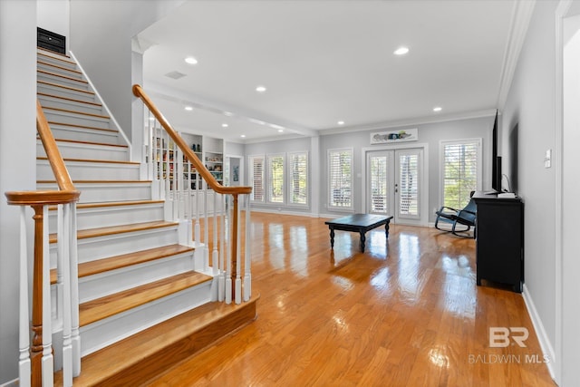 foyer with ornamental molding, a healthy amount of sunlight, french doors, and light wood-type flooring