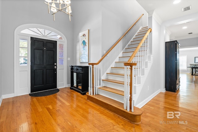 entrance foyer featuring a high ceiling, a healthy amount of sunlight, a notable chandelier, and hardwood / wood-style flooring