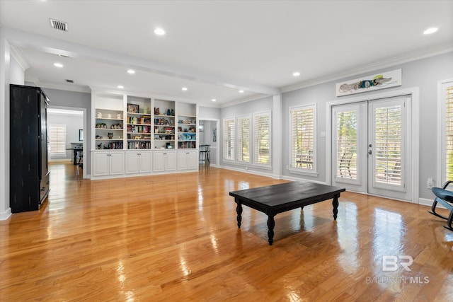 living room with crown molding, french doors, light hardwood / wood-style floors, and built in features