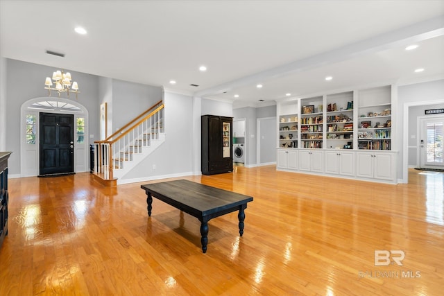 living room with an inviting chandelier, washer / clothes dryer, and light hardwood / wood-style flooring