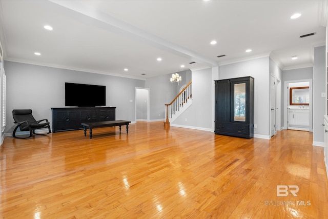 living room featuring light hardwood / wood-style flooring, ornamental molding, and a notable chandelier