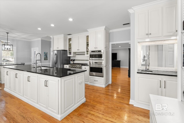 kitchen with sink, an island with sink, light hardwood / wood-style flooring, and appliances with stainless steel finishes