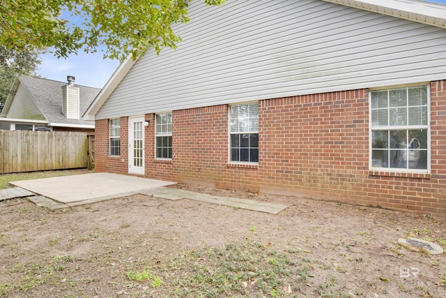 back of property with brick siding, fence, and a patio