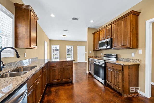 kitchen featuring kitchen peninsula, stainless steel appliances, sink, and light stone counters