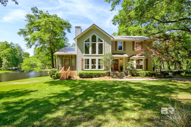 view of front facade with a front lawn, a chimney, metal roof, and a water view