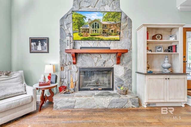 living area with wood finished floors, visible vents, and a fireplace