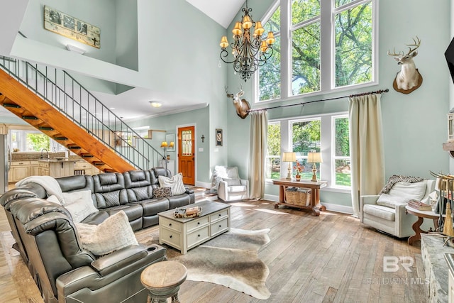 living area with hardwood / wood-style flooring, high vaulted ceiling, a notable chandelier, and stairway