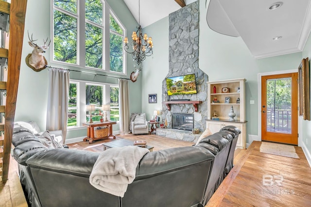 living area with light wood-style flooring, baseboards, an inviting chandelier, a fireplace, and high vaulted ceiling