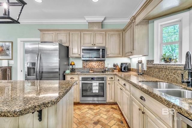 kitchen featuring ornamental molding, a sink, brick floor, decorative backsplash, and appliances with stainless steel finishes