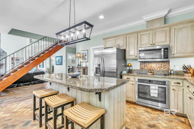 kitchen featuring brick floor, cream cabinetry, appliances with stainless steel finishes, and crown molding