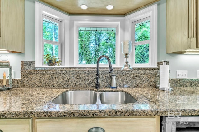 interior details with wine cooler, a sink, dark stone counters, decorative backsplash, and light brown cabinets