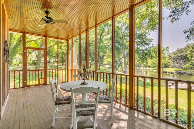 sunroom featuring outdoor dining area, a water view, and ceiling fan