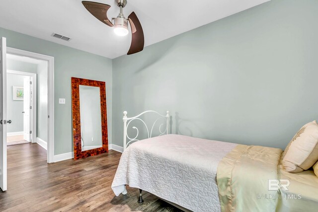 bedroom with wood finished floors, visible vents, a ceiling fan, and baseboards