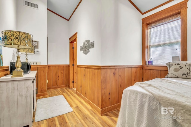 bedroom featuring wainscoting, visible vents, light wood-style floors, and crown molding