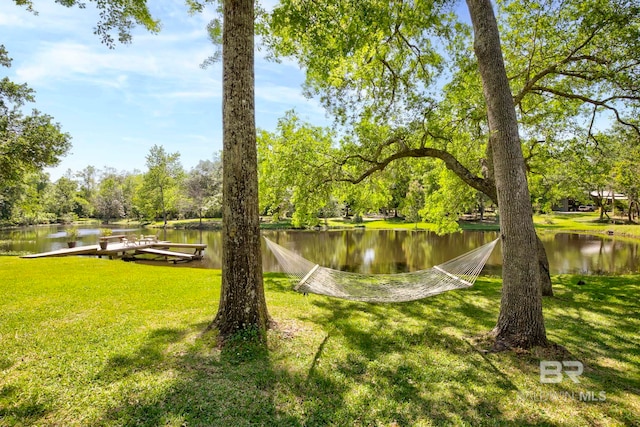 view of home's community with a dock, a yard, and a water view