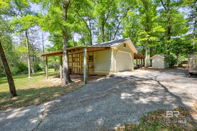 exterior space with metal roof, an outbuilding, and aphalt driveway