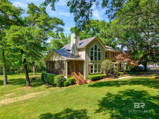 rear view of property with a yard, a sunroom, and a chimney