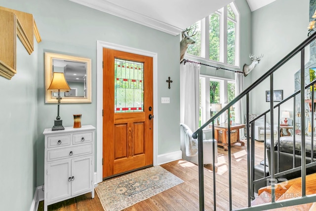 entrance foyer featuring stairway, baseboards, wood finished floors, and ornamental molding