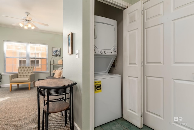 washroom featuring ceiling fan, stacked washer and clothes dryer, light colored carpet, and ornamental molding