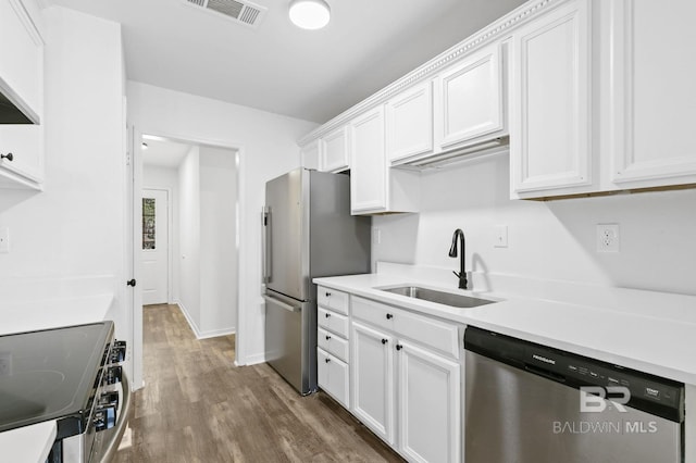 kitchen with sink, appliances with stainless steel finishes, dark hardwood / wood-style floors, and white cabinetry