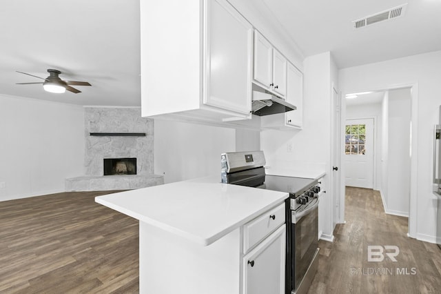 kitchen featuring electric range, a stone fireplace, ceiling fan, dark hardwood / wood-style floors, and white cabinetry