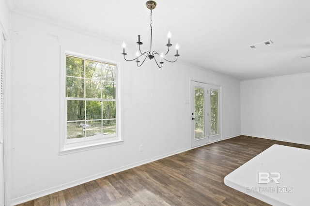 unfurnished dining area with dark wood-type flooring, a notable chandelier, and crown molding