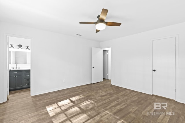 unfurnished bedroom featuring sink, ensuite bathroom, ceiling fan, a closet, and dark hardwood / wood-style floors