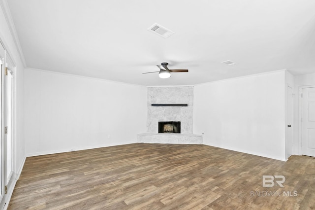 unfurnished living room with ceiling fan, ornamental molding, a fireplace, and wood-type flooring