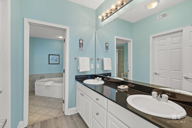 bathroom with wood-type flooring, shower with separate bathtub, and vanity