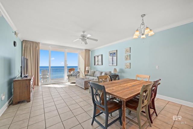 tiled dining area with ceiling fan with notable chandelier, a wall of windows, and crown molding