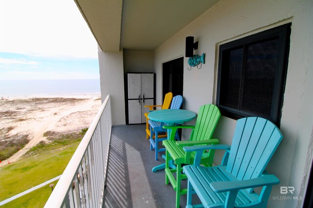 balcony with a water view and a view of the beach