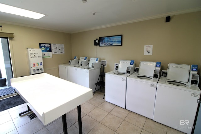 washroom with crown molding, washing machine and dryer, and light tile patterned flooring