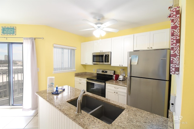 kitchen with appliances with stainless steel finishes, white cabinetry, light stone countertops, and sink