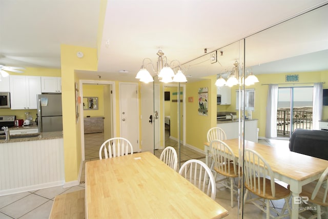 dining space with ceiling fan with notable chandelier and light tile patterned flooring