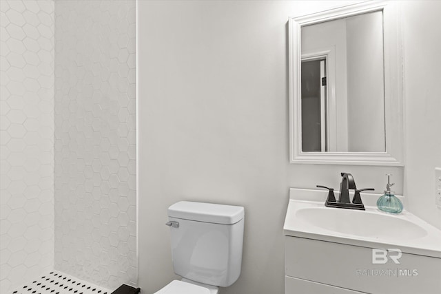 bathroom featuring tiled shower, vanity, and toilet