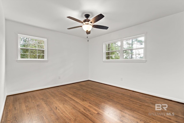 empty room featuring ceiling fan, a healthy amount of sunlight, and hardwood / wood-style flooring