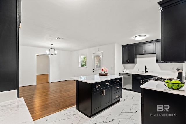 kitchen with sink, hanging light fixtures, stainless steel dishwasher, light wood-type flooring, and a kitchen island