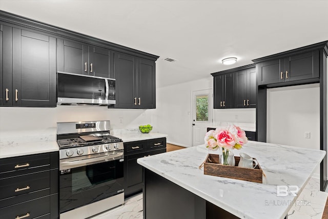 kitchen featuring a kitchen island, light stone countertops, and appliances with stainless steel finishes