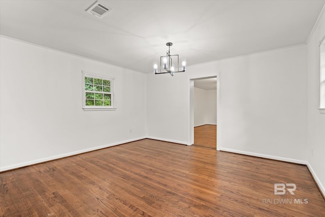 empty room featuring hardwood / wood-style floors, a notable chandelier, and ornamental molding