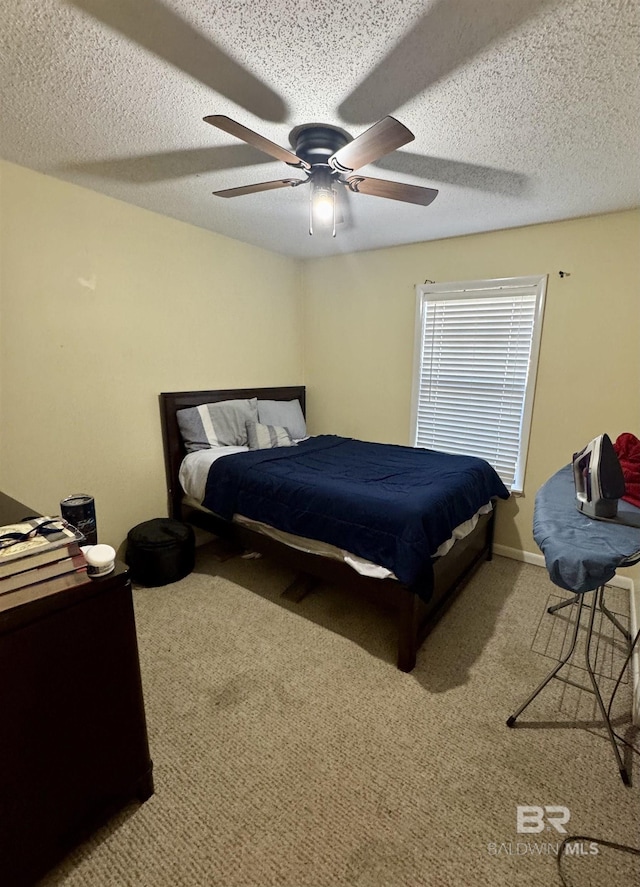 carpeted bedroom with ceiling fan and a textured ceiling