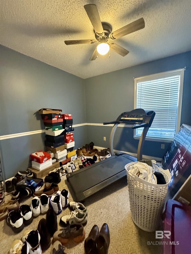 exercise area with ceiling fan, carpet floors, and a textured ceiling