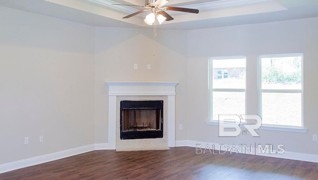 unfurnished living room with a fireplace, dark hardwood / wood-style flooring, a raised ceiling, and ceiling fan