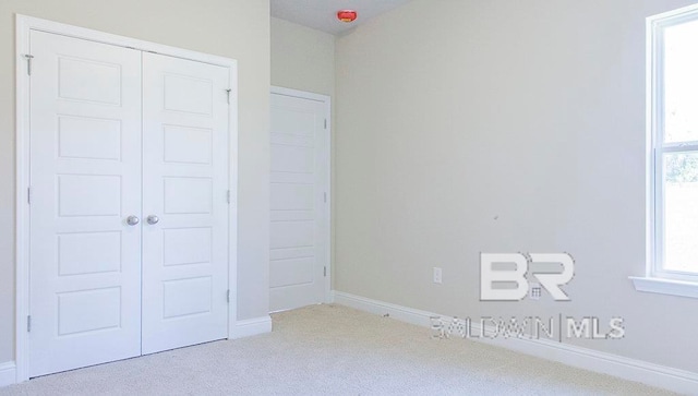 unfurnished bedroom featuring light carpet and a closet