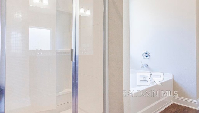 bathroom featuring plus walk in shower and hardwood / wood-style flooring