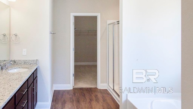 bathroom with vanity, hardwood / wood-style floors, and plus walk in shower