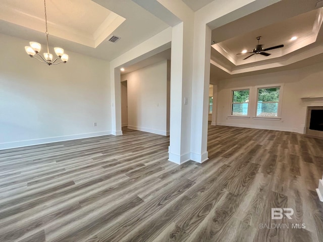 unfurnished living room with hardwood / wood-style floors, ceiling fan with notable chandelier, and a raised ceiling