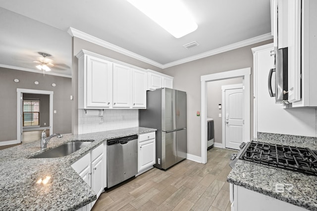 kitchen with sink, stainless steel appliances, light stone counters, white cabinets, and ornamental molding