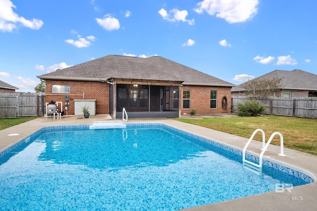 view of swimming pool featuring a yard, a patio area, and a sunroom