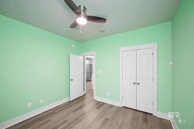 unfurnished bedroom featuring ceiling fan, stainless steel fridge, light hardwood / wood-style floors, and a closet